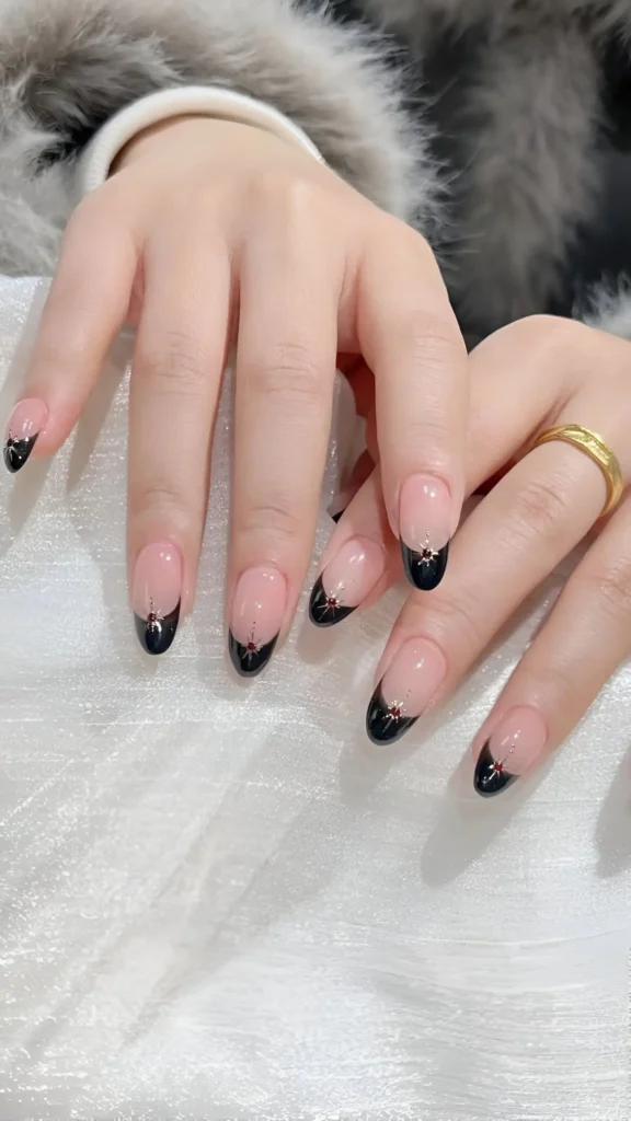 Almond-shaped nails with black French tips on a sheer base, featuring a tiny sparkle accent at the center of each tip's base line.