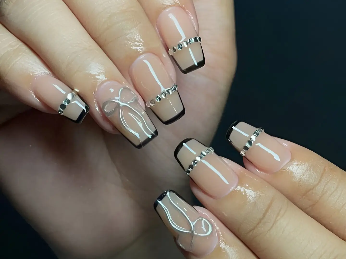 Chic square nails with black French tips, rhinestone details, and silver bow line art, representing cool nail design ideas.
