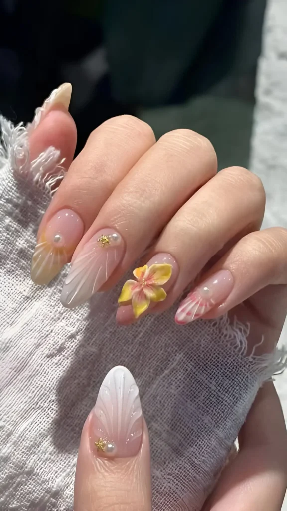 Cute pink sheer nail design with 3D sculpted white shells, 3D flowers, pearls, and gold stars.