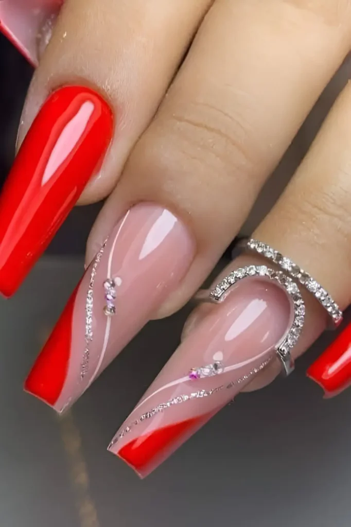 Glamorous red and pink nail design with silver glitter swirls and rhinestones on long square nails.
