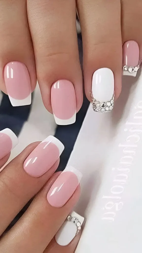 Cute pink and white French manicure with white accent nail featuring rhinestone cuticle curve.