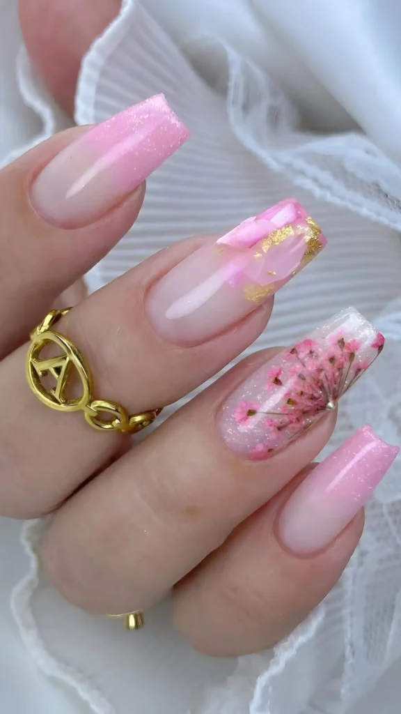 Cute pink nail design with glitter ombre, encapsulated dried flowers, and marble gold foil accents.