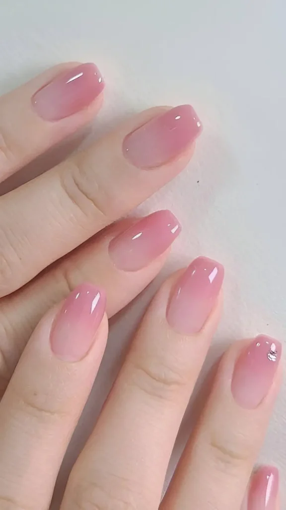 Cute pink ombre nail design with sheer base, jelly pink tips, and single tiny rhinestone accent.