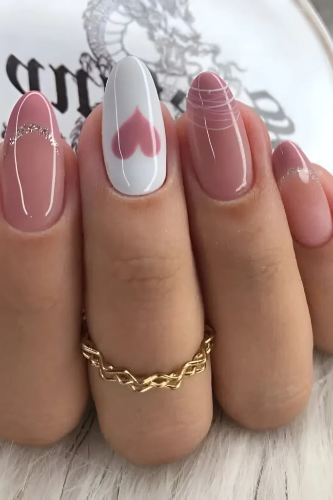 Cute pink and white nail design with mauve pink heart accent, silver glitter cuticle curve, and white line art.