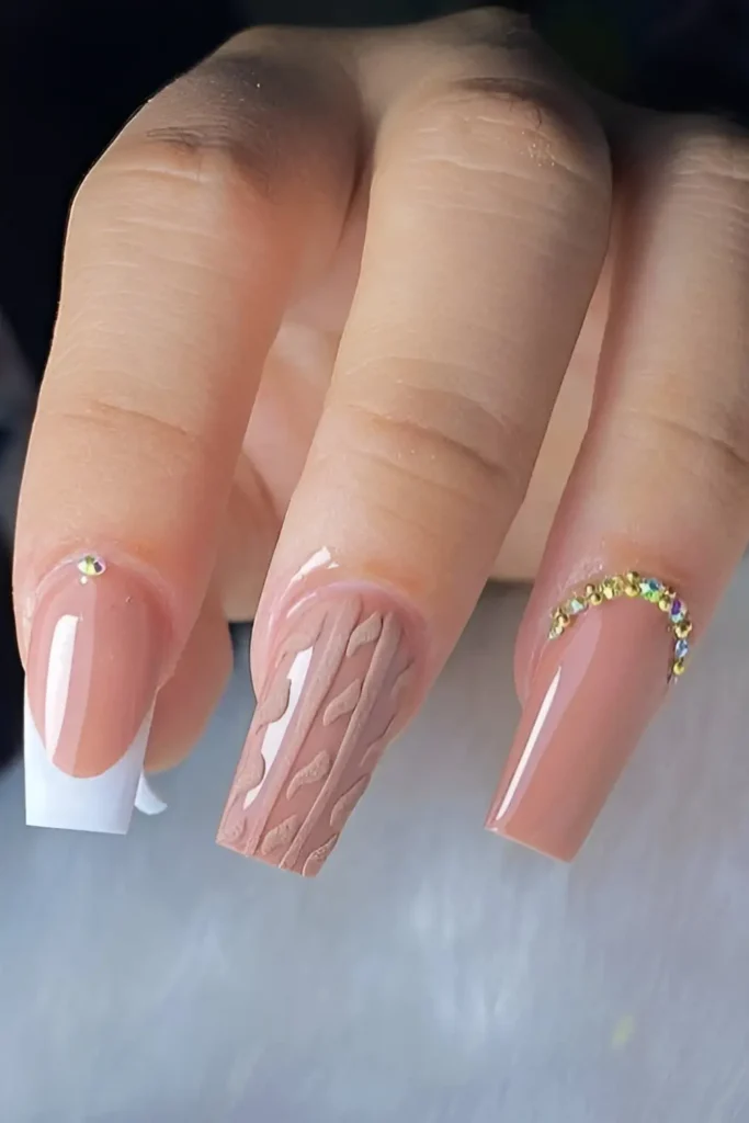 Cute nude-pink nail design with 3D cable knit sweater texture accent and rhinestone details.