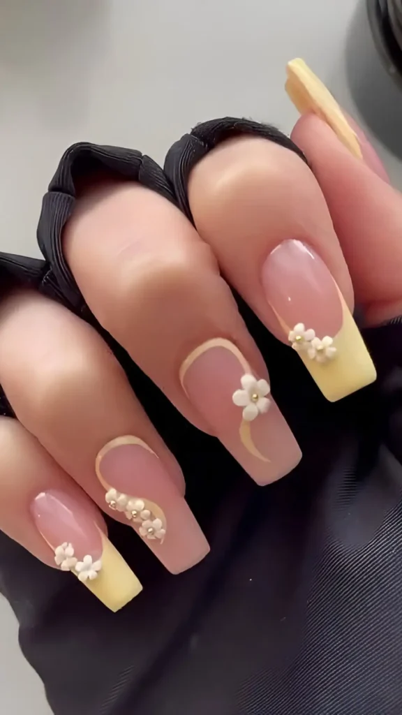 Cute pink base nail design with pale yellow French tips, white curve lines, and 3D white flower clusters.