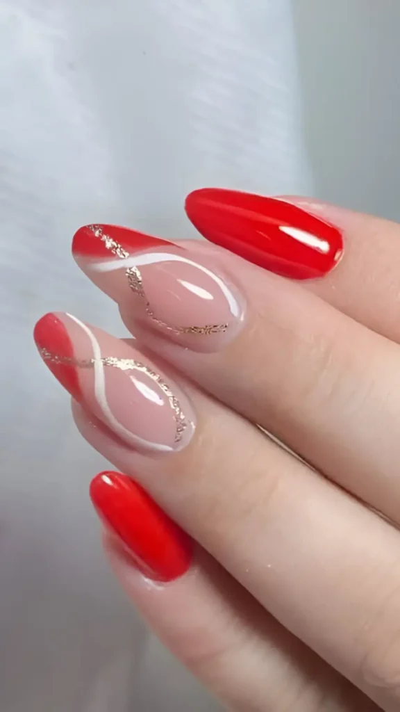Cute pink and red nail design with white curves and gold glitter line details on almond nails.