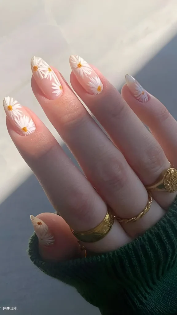 Cute sheer pink nail design on almond nails with small scattered white daisy flowers.