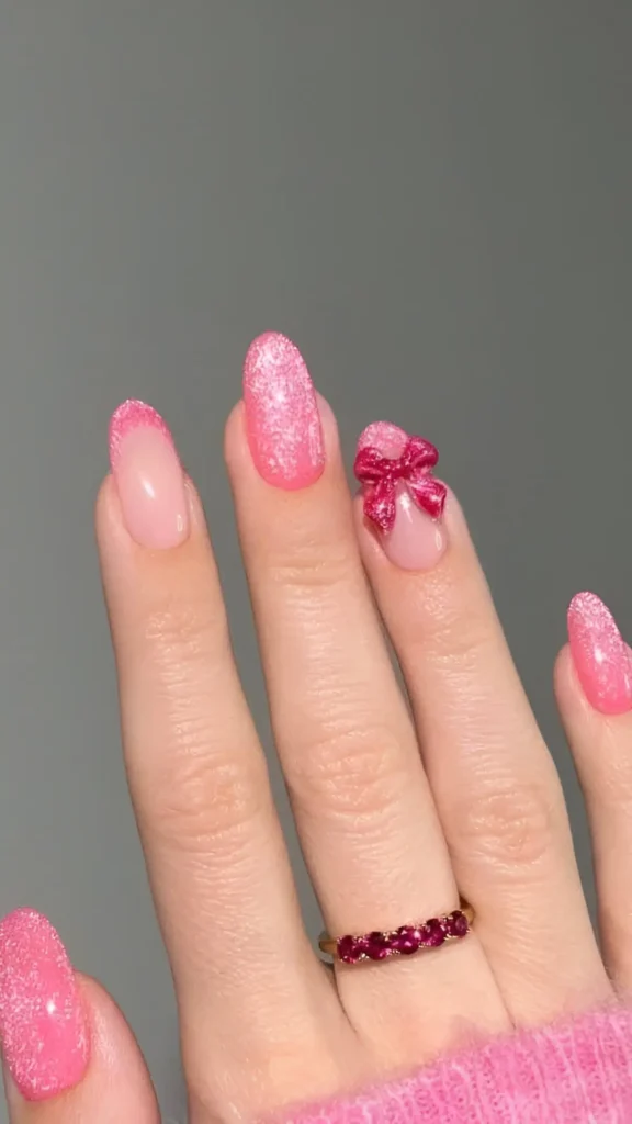 Cute pink glitter nails with 3D sparkly pink bow accent on oval nails.