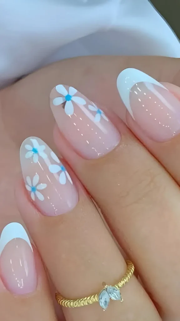 Cute pink base nail design with classic white French tips and scattered light blue flower accents.