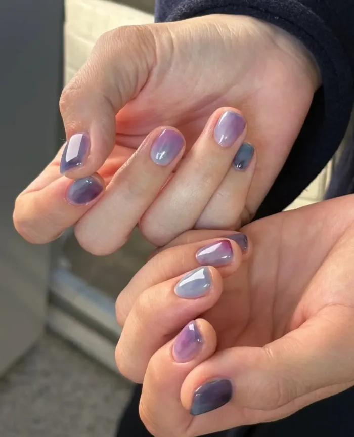 Gel manicure on short rounded nails featuring a cute smoky purple and grey-blue aura gradient effect.