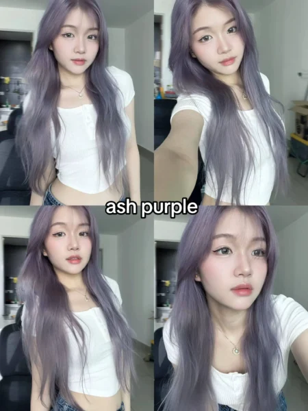 Young woman, potentially of East Asian descent, with long, slightly wavy ash purple hair featuring curtain bangs, showcasing a muted 2025 hair color trend.