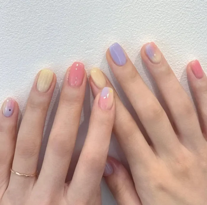 Cute simple gel nail idea with mixed pastel colors including pink, yellow, and lavender, some with soft gradients and tiny star accents.