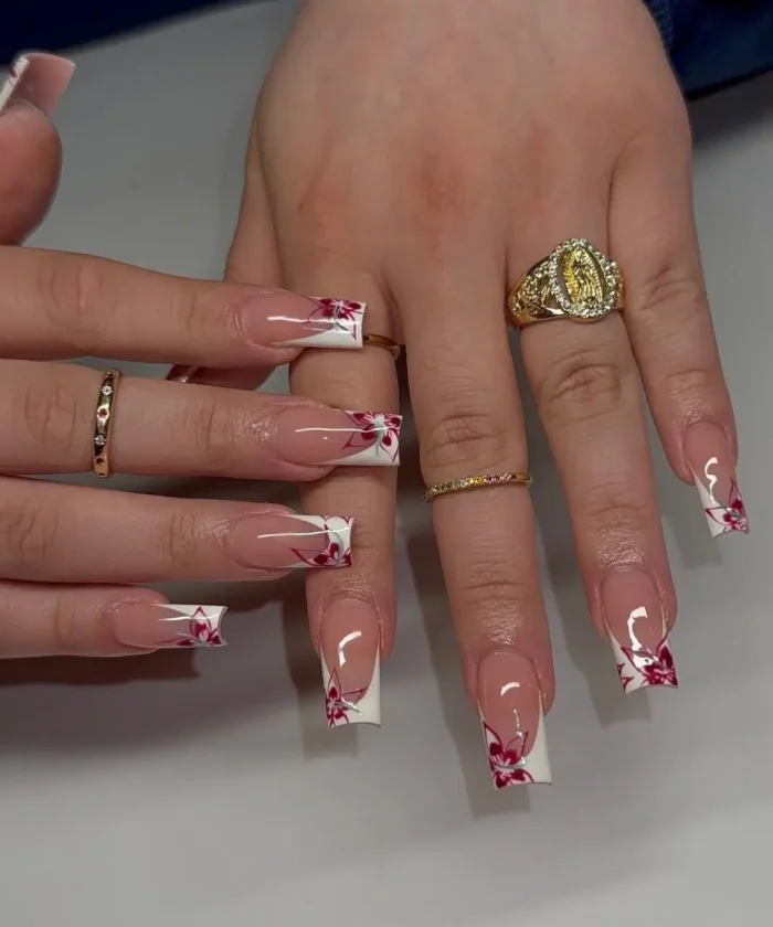 Long square nails showcasing a pristine white French tip, artistically detailed with a vibrant red and pink floral design.