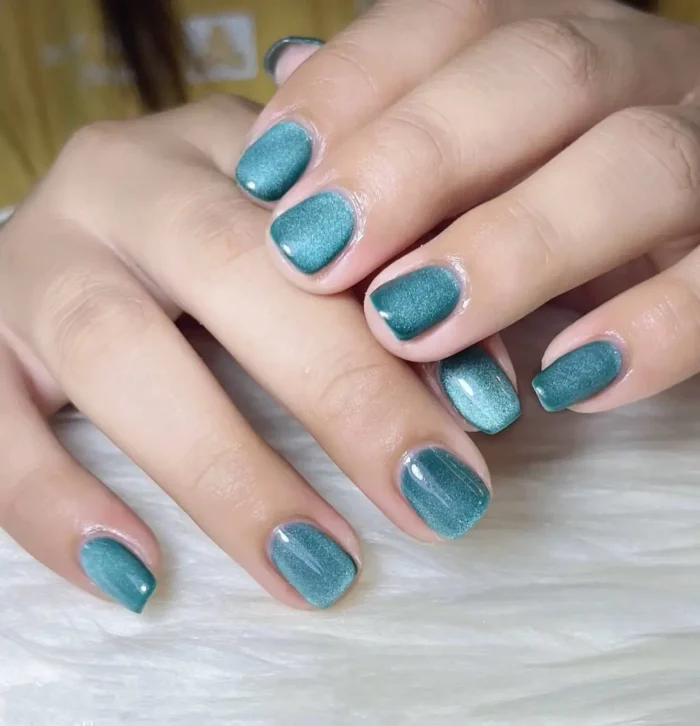 Cute simple gel nails in a luminous deep teal shimmer, creating a velvet effect on short squoval nails.
