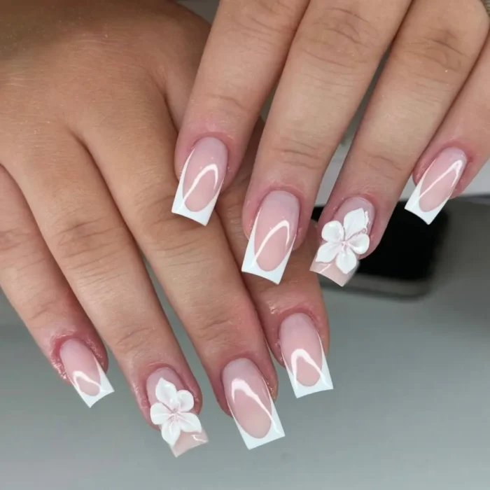 Square-shaped nails with a classic white French manicure, accented by detailed 3D white sculpted flowers.