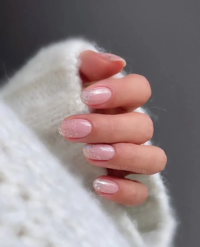 Sheer pink short nails with a delicate glitter ombre fade at the tips, creating a subtle sparkling effect.