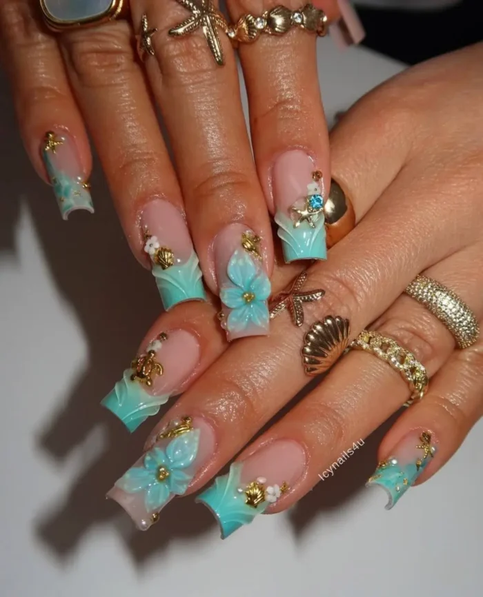 A maximalist under-the-sea nail art design with sculpted turquoise tips, 3D flowers, and gold seashell and turtle charms.