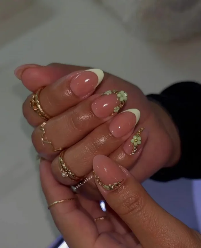 Elegant almond-shaped nails with a soft off-white French tip, exquisitely detailed with pale green 3D flower embellishments and fine gold bead accents.