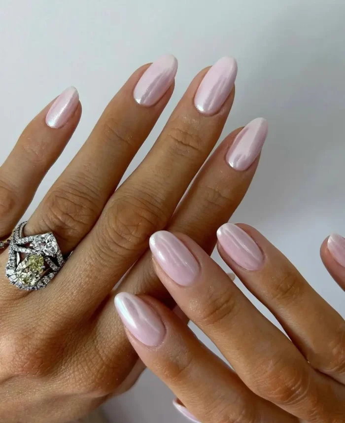 Long almond-shaped nails in soft pearlescent pink, featuring a luminous 'glazed donut' chrome finish.