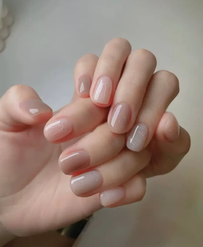 Cute simple gel manicure with sheer nude base, subtle wispy white line art, and hints of sparse shimmer on short nails.