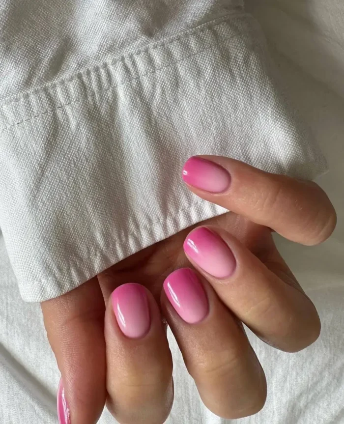 Cute simple gel manicure with a vibrant cheerful pink ombre fade on short rounded nails.