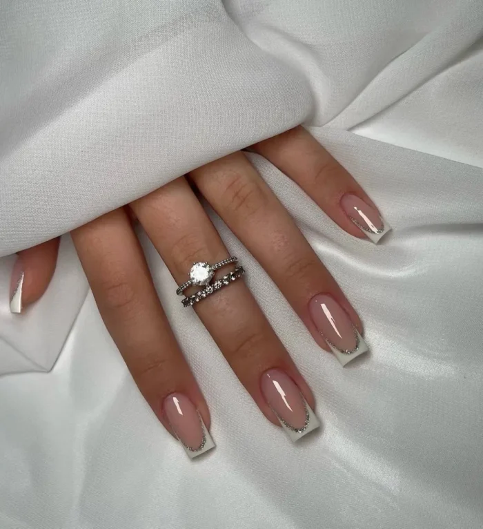 Clean square-shaped nails with a classic white French manicure, beautifully accented with a fine silver glitter line along the smile curve.