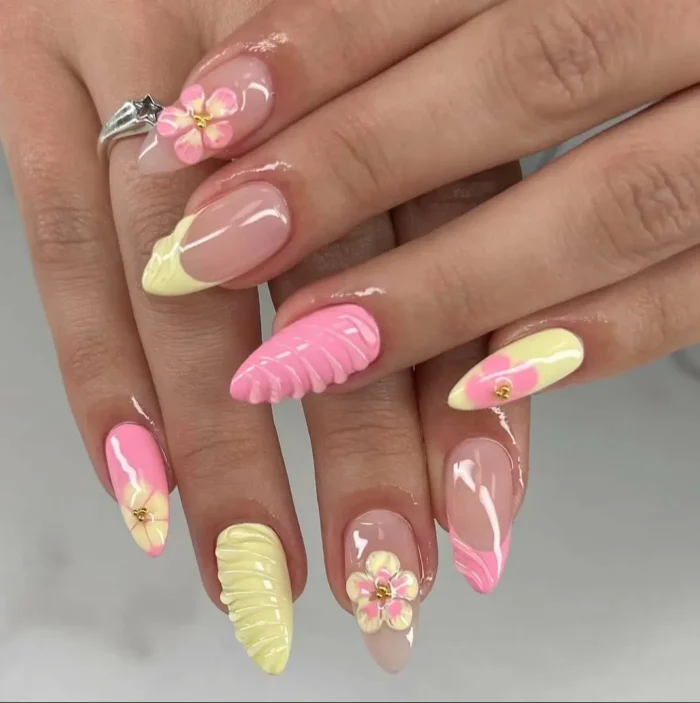 A dynamic manicure on almond-shaped nails featuring a mix of butter yellow and pink designs, including 3D textures, floral art, and French tips.