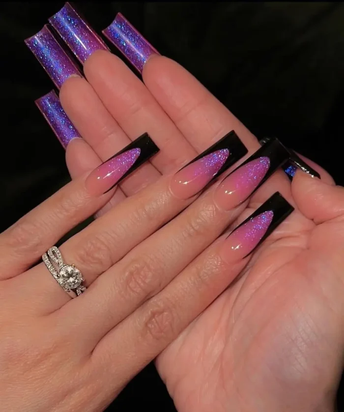 Ultra-glam coffin nails with a fuchsia glitter fade purple nail design, featuring a sharp black tip over sparkling ombré.