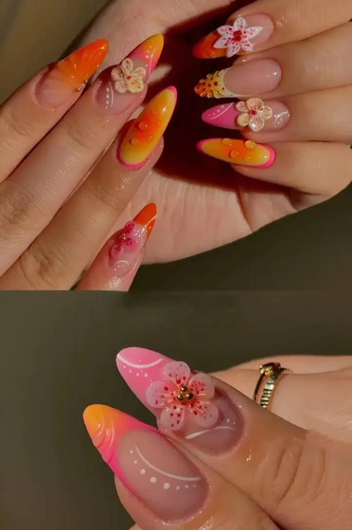 Long almond nails with a pink and orange ombré, 3D floral details, and clear dewdrop accents for a tropical nail art inspo.