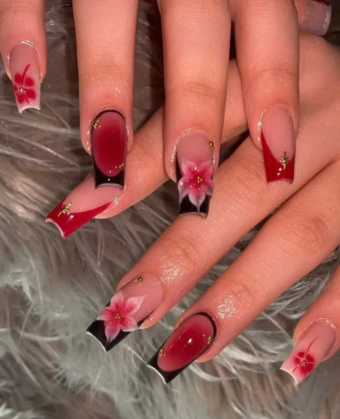 Long square nails with a striking black and red themed French design, featuring ombré tips, elaborate 3D reddish-pink flowers, and subtle gold stud details.