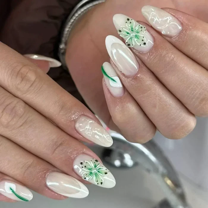 Milky white almond nails with hand-painted green foliage and 3D green and white speckled flowers.