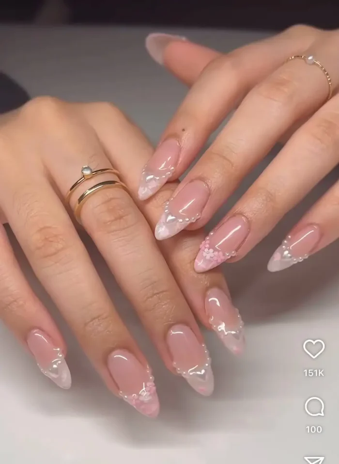 An elegant French manicure on almond nails with pearlescent, iridescent tips and tiny, delicate floral details for a romantic twist.