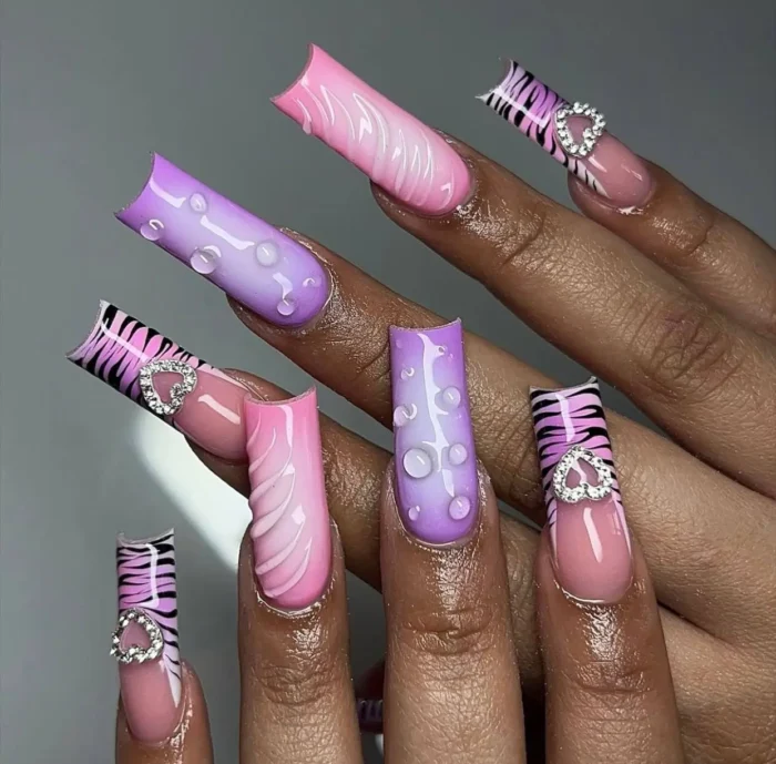 Y2K purple pop drops nail design on flared nails, featuring vibrant purple and pink ombré with 3D water droplets and heart charms.
