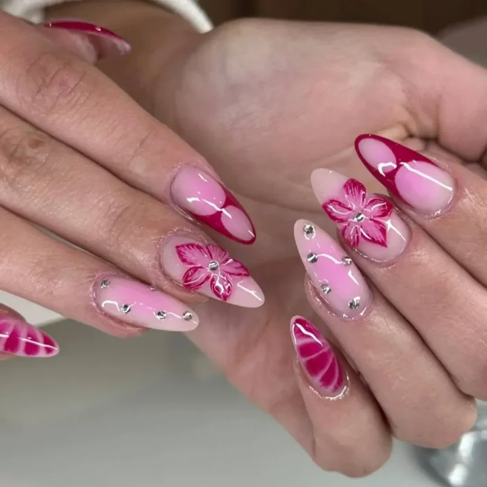 Long almond nails with fuchsia color-blocking, swirls, 3D fuchsia flowers, and scattered silver rhinestones.