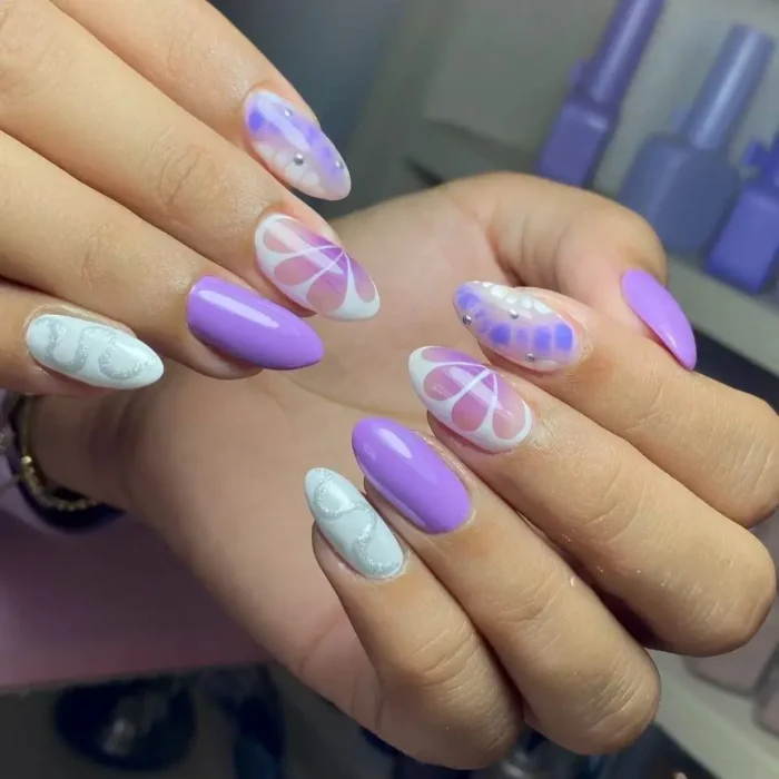 A mix-and-match lavender manicure on almond nails, with white stars and a silver chrome snake design as nail art inspo.