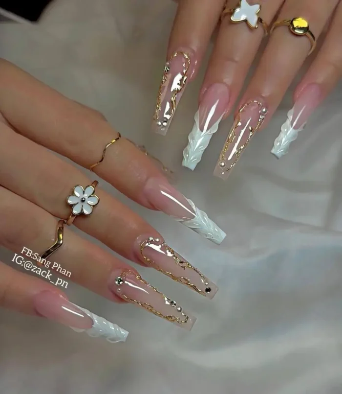 Long nails showcasing 3D white cable-knit textured French tips and elegant gold swirl designs with rhinestone accents.