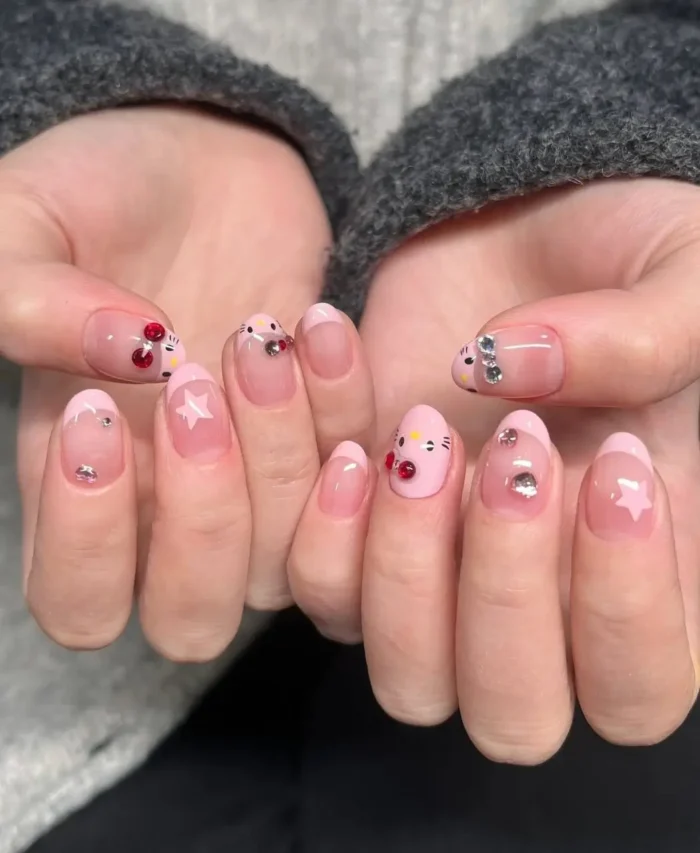 An adorable kawaii character manicure with sparkling gem details and playful star motifs over a sweet pink French tip.