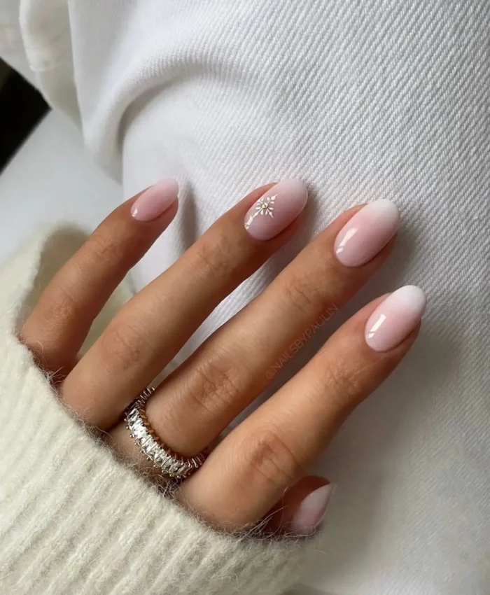 Oval-shaped baby pink and white ombre nails with a charming white daisy accent on one finger.