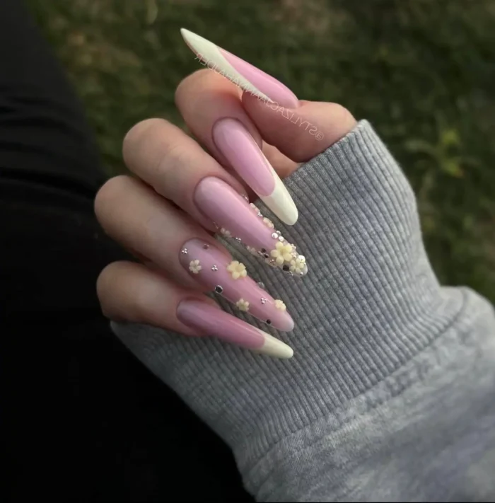 Long almond nails with pale yellow French tips for summer, accented with tiny 3D flowers and pearls for a subtle, dainty look.
