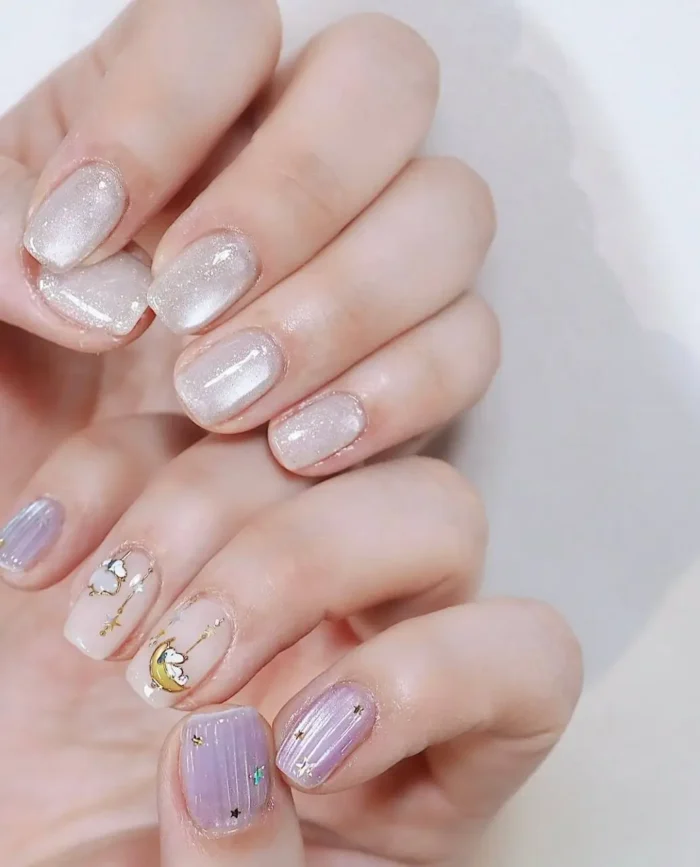 Cute simple gel manicure with pearlescent shimmer, lavender, and gold celestial moon and star designs on short nails.