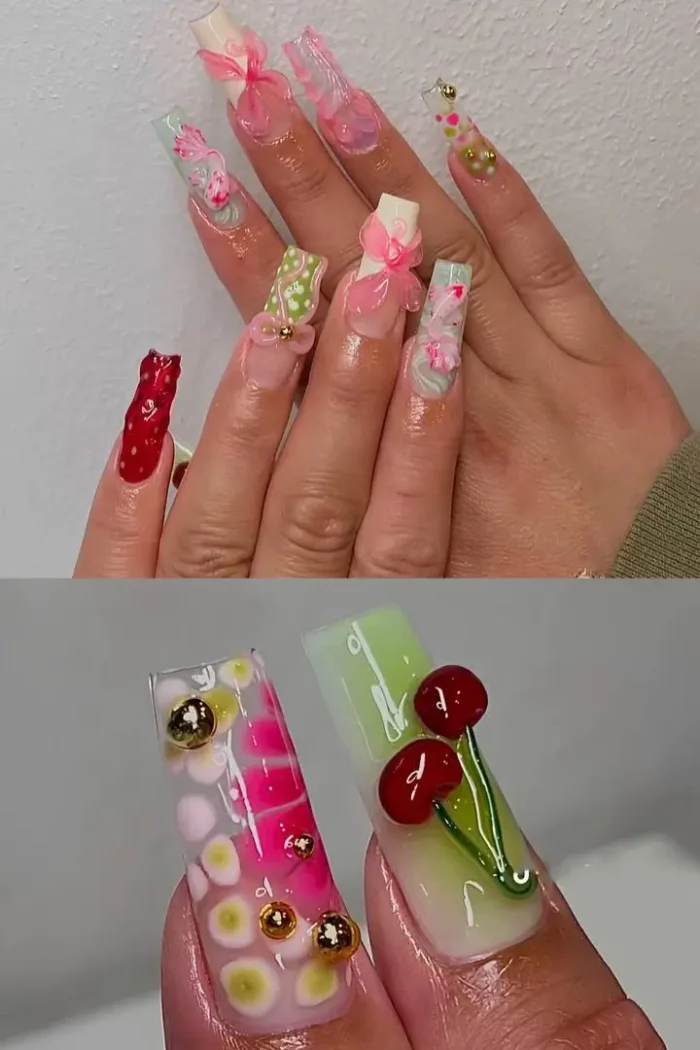 A pink mix-and-match manicure on long stiletto nails, featuring a 3D bow, smiley face art, and hearts for a barbie-core aesthetic.