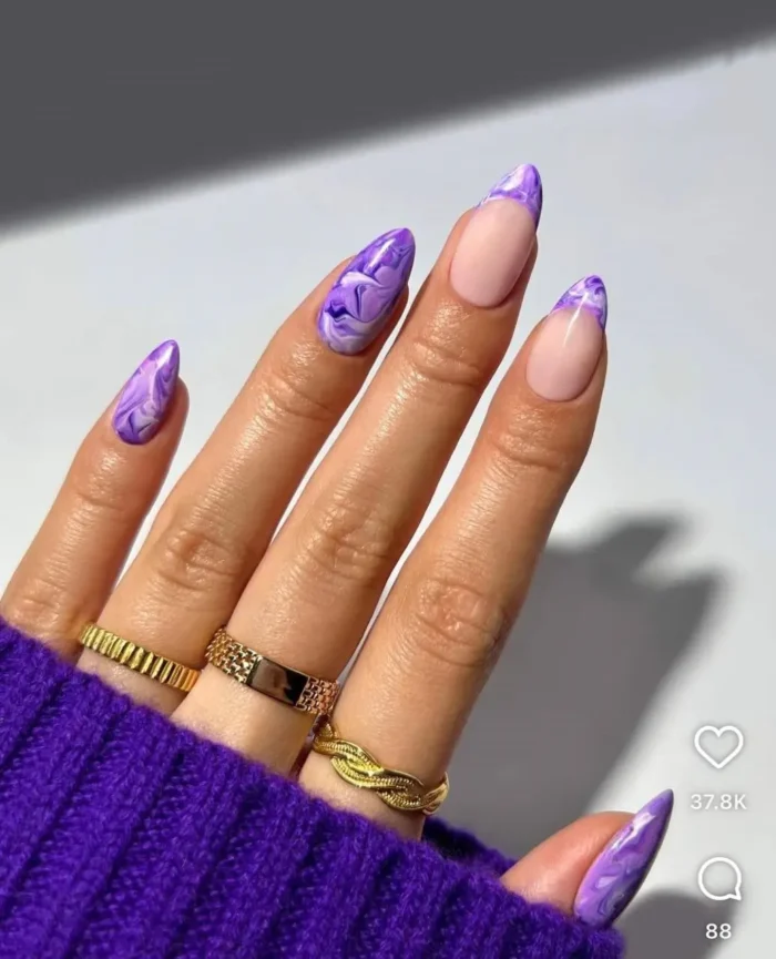 Close-up of amethyst marble tips on almond nails, an artistic purple nail design with white swirls and a French tip style.