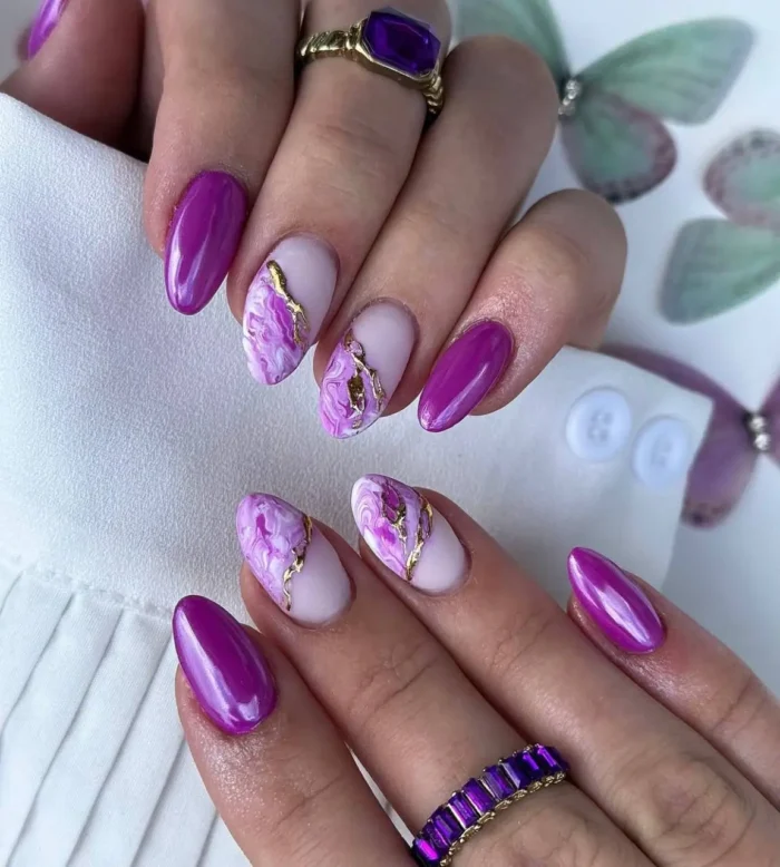Oval-shaped nails with a mauve marble luxe purple nail design, featuring magenta-purple polish and marble with gold veins.