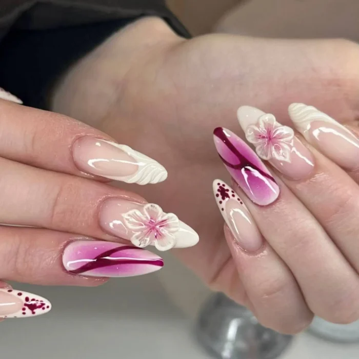 Almond nails with a pink ombré base, sculpted white French tips, and delicate semi-translucent 3D flowers.