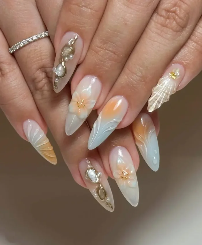 Sophisticated ocean-themed summer nails on long almonds, featuring sculpted seashell textures, soft ombre, 3D flowers, and pearls.
