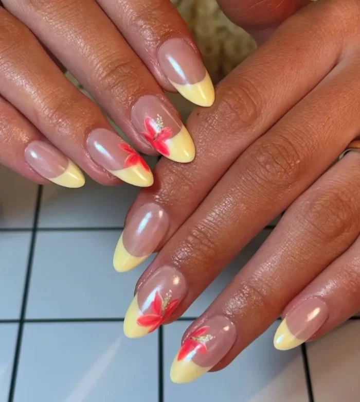 Butter yellow French manicure with accent nails featuring bright red-orange hibiscus flower art.