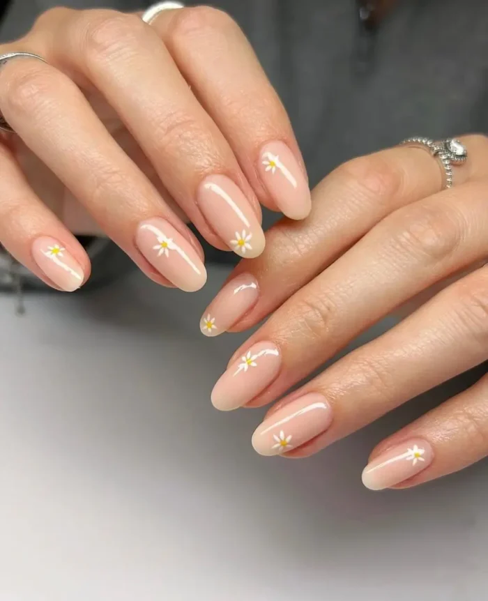 Oval nails with a milky, sheer base beautifully decorated with a delicate chain of tiny white daisies.