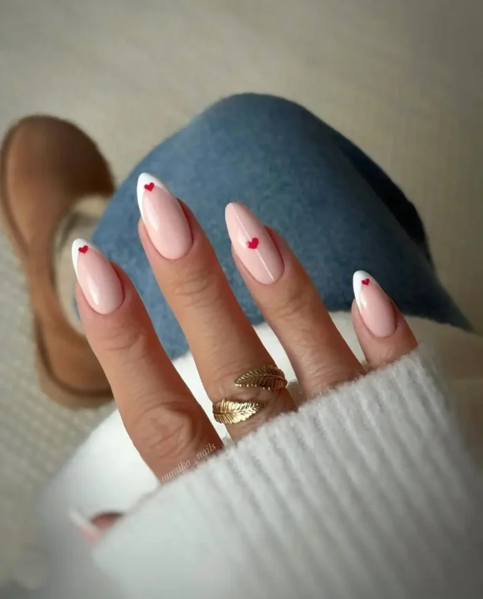 A chic and minimalist French manicure featuring a flawless white tip and a single, perfect tiny red heart—a very cute nail idea.