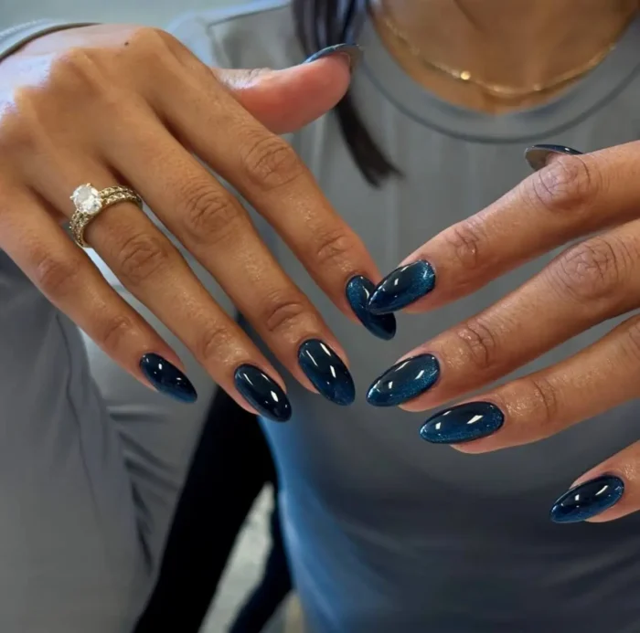 Cute simple gel manicure with a striking deep sapphire blue cat-eye effect on medium almond-shaped nails.